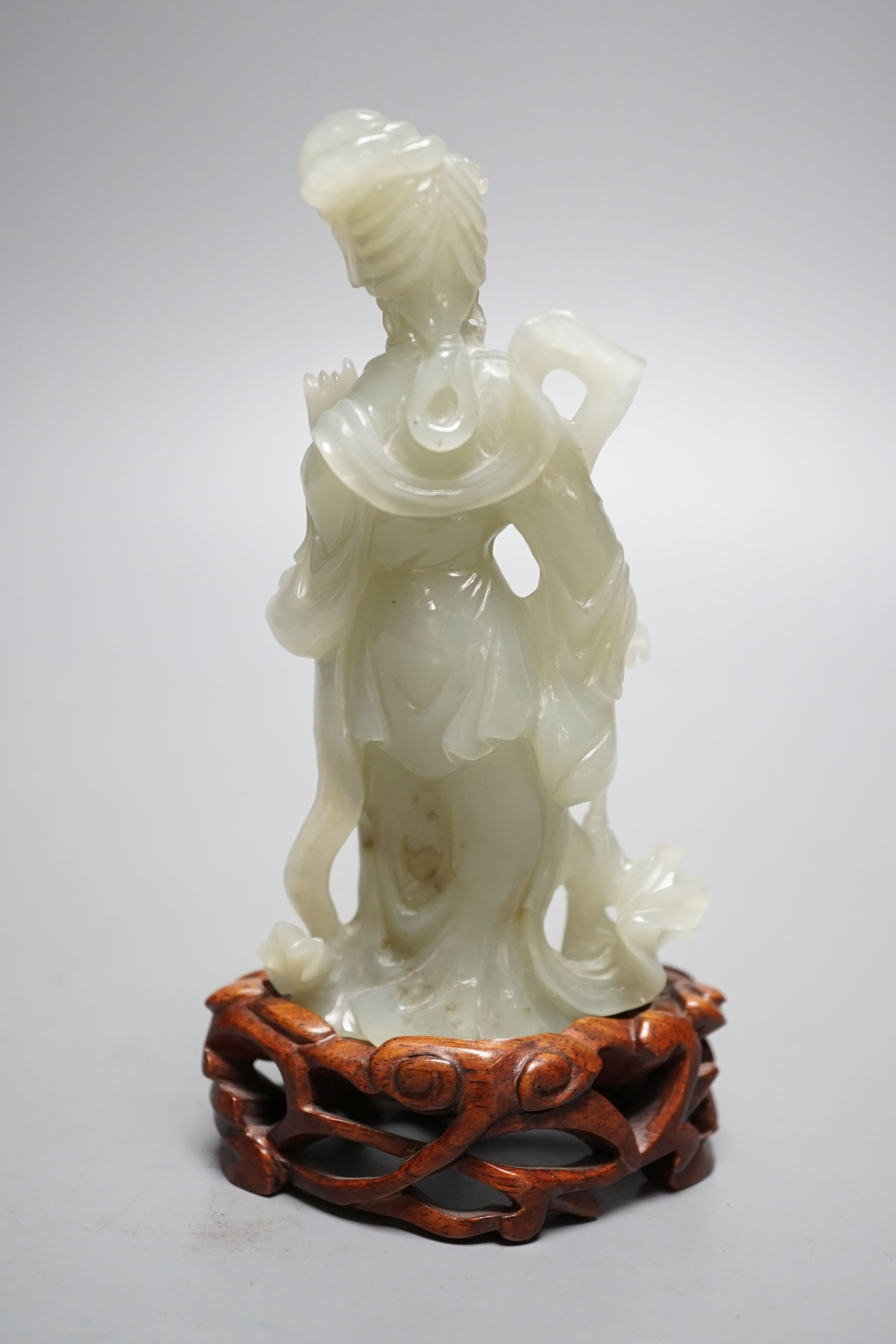 A Chinese celadon jade figure of a lady wood stand, 13 cms high.